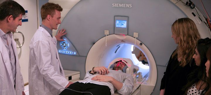 Researchers standing beside an MRI scanner with a participant