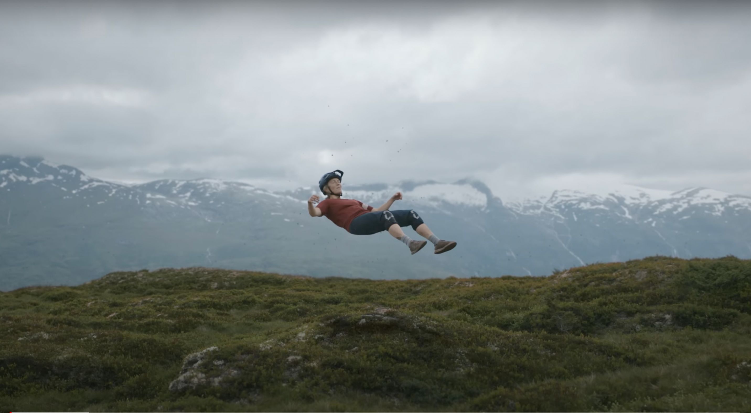 Mountain biker Olly Wilkins airborne mid-jump, snow-capped mountains in the background