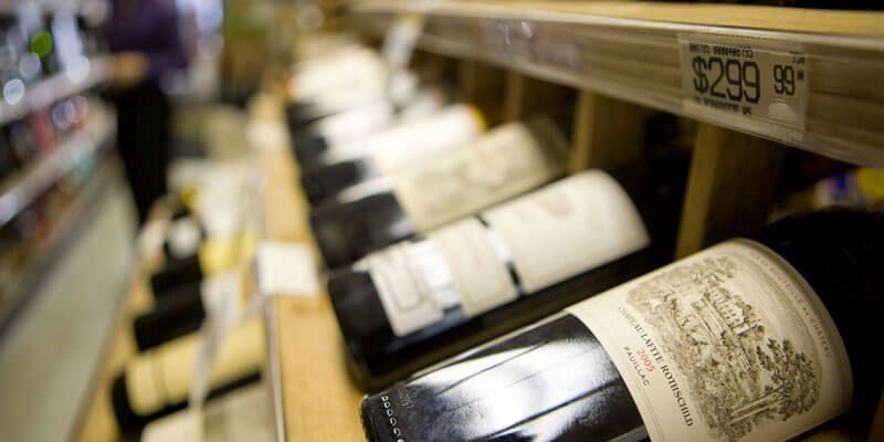 Wine bottles displayed on a shop shelf, with a price tag reading $299.99 visible in the background
